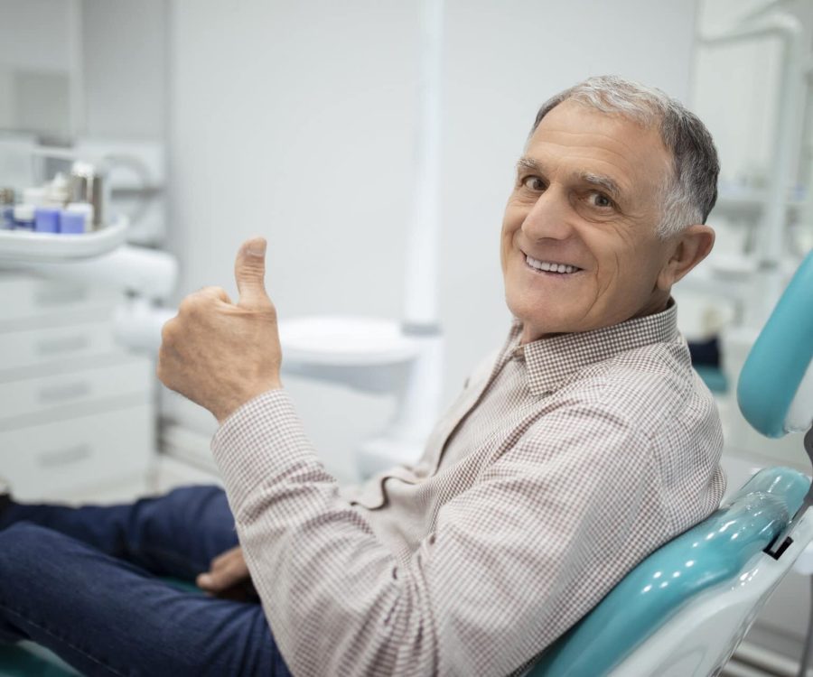 Old senior man sitting in a dental chair thumb up