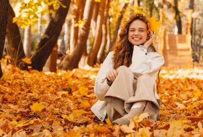 smiling-young-woman-sits-in-the-autumn-foliage-on-2023-10-11-19-59-30-utc